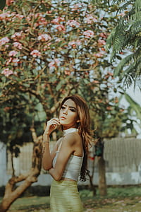 selective focus photography of woman standing near flowering trees thumbnail