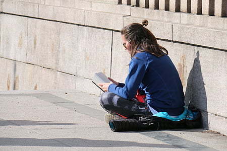 woman wearing blue denim jacket and black pants reading book thumbnail