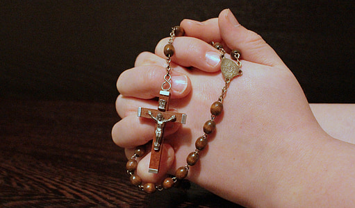 person holding brown rosary necklace thumbnail