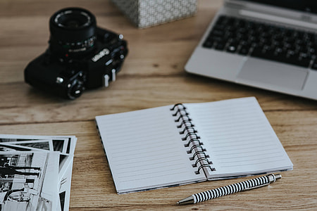 Black-and-white photos with a silver laptop, a smartphone, car keys, pencils and a camera thumbnail