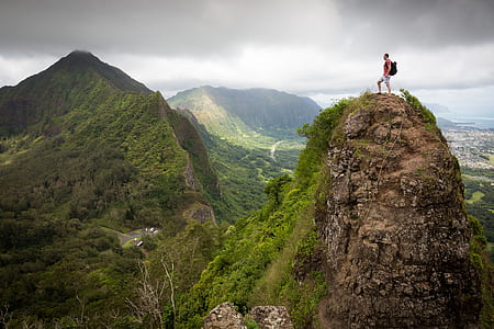photography of man wearing backpack standing on cliff thumbnail