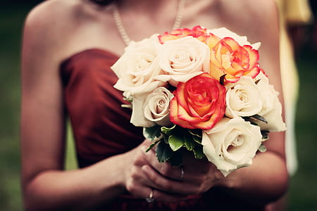 woman in brown tube top holding white and red petaled flowers thumbnail