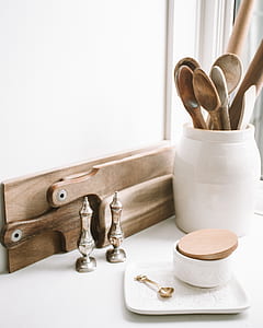 white ceramic container with spoons and condiment shaker on white table thumbnail