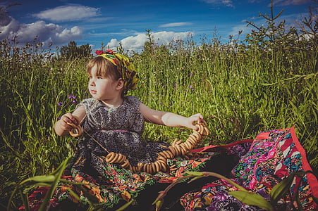 girl wearing floral dress sitting on green grass thumbnail