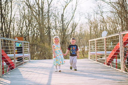 boy and girl holding each others hand while walking on bridge thumbnail