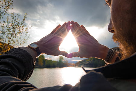 man covering the sun using his hands thumbnail