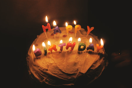 cake with Happy Birthday lighted candle inside dark room thumbnail