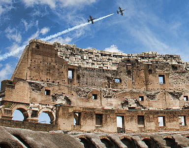 closeup photography of brown Colosseum under two aircrafts thumbnail