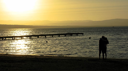 silhouette photo of two person at seashore during golden hour thumbnail