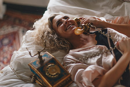 woman lying on bed holding rotary phone thumbnail