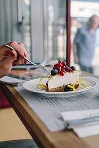 Woman Enjoying Cheese Cake and a Coffee with Fruits in a Cafeteria thumbnail