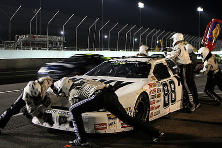 people repairing white stock car during nighttime thumbnail