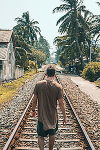 man walking in train tracks thumbnail