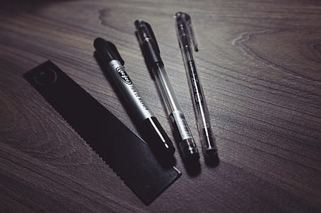 Three Ballpoint Pens and Black Ruler on Beige Wooden Surface thumbnail
