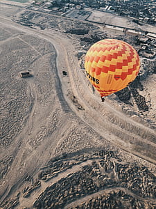 red and yellow hot air balloon flying over city thumbnail