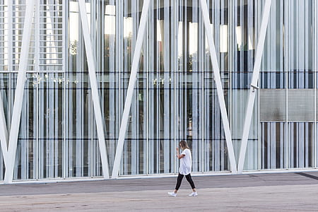 woman walking on street beside glass building thumbnail