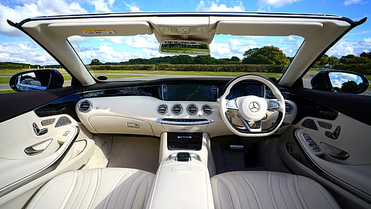 grey and black Mercedes-Benz vehicle interior overlooking green grass field and trees under cloudy sky during daytime thumbnail