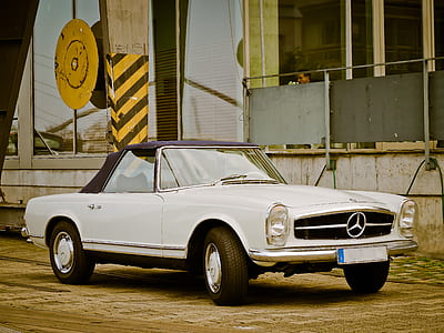 white Mercedes-Benz soft-top coupe parked near grey buildiung thumbnail
