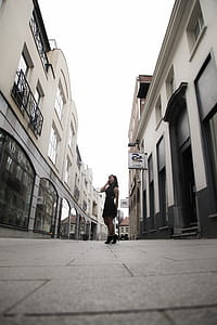 Woman Wearing Black Sleeveless Dress in Between Buildings thumbnail
