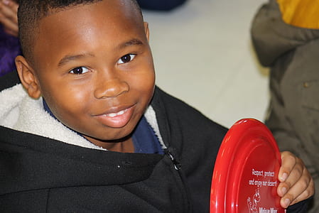 boy wearing black hoodie holding red plastic toy thumbnail