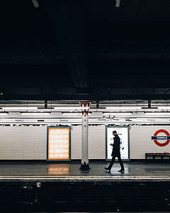 man walking along sidewalk of train station thumbnail