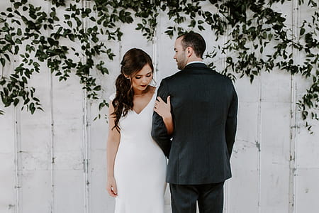 woman in gown and man in suit standing close together near the wall thumbnail