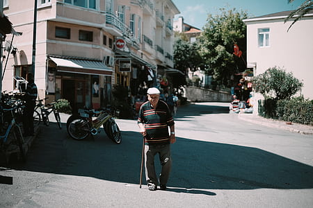 photo of man standing on concrete road while using walking cane thumbnail