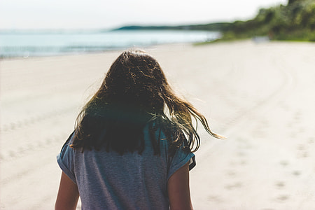 woman walking on seashore during daytime thumbnail