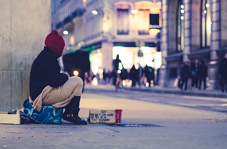 person sitting beside wall near road thumbnail