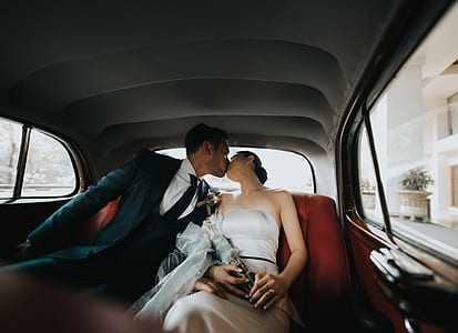 shallow focus photography of groom and bride kissing in car thumbnail