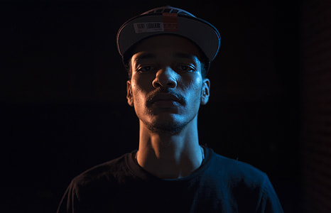 man wearing hat with plain black background thumbnail
