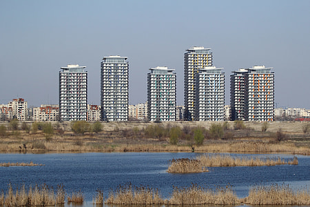 city building near body of water under clear sky thumbnail