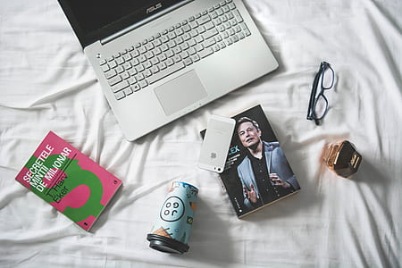 silver iPhone 5s on Elon Musk book beside eyeglasses and Asus laptop thumbnail