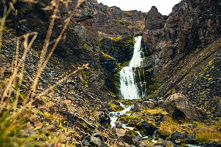 A hiker resting on a rock by the glacier waterfall in the mountains thumbnail