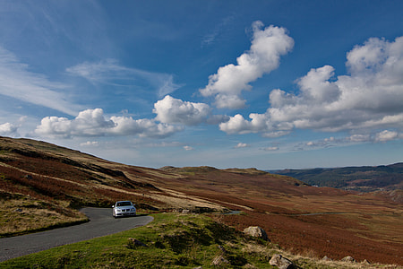 A BMW car drives along an open and twisting road in the Lake District in Cumbria, England thumbnail