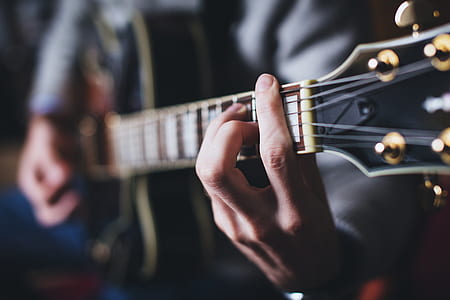 selective focus photography of person playing guitar thumbnail