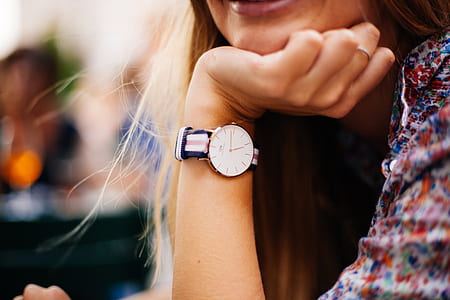 woman wearing round gold-colored analog watch with white-red-and-blue striped strap thumbnail