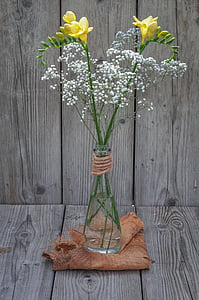 yellow and white petaled flowers inside vase on wooden surface thumbnail