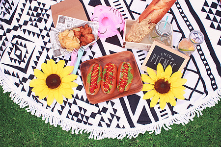 three hotdog sandwiches, chicken nuggets and chips, and baguette on picnic mat thumbnail