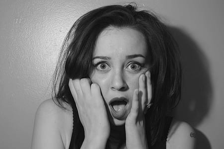 grayscale of woman holding her cheeks while wearing black tank top thumbnail