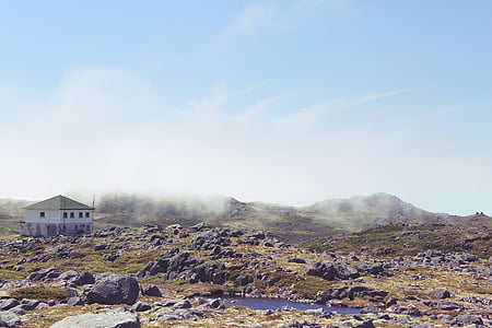 white concrete house on mountain under gray sky thumbnail