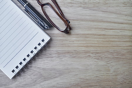 steno notebook beside black pen and brown framed eyeglasses thumbnail