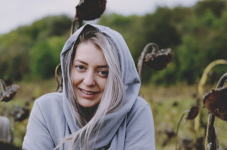 woman sitting beside brown flowers while smiling during daytime thumbnail