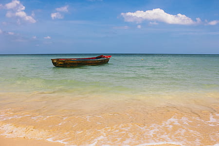 A boat in shallow water of a clear blue ocean thumbnail