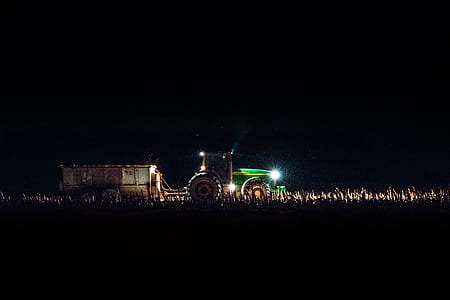 green tractor with lights turned on at night thumbnail