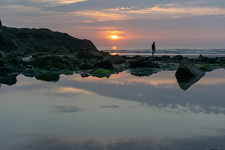 person standing on rock near body of water thumbnail