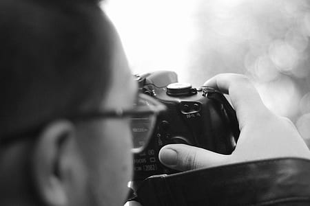 grayscale photography of man using DSLR camera thumbnail