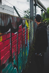 man holding spray paint standing in front of graffiti art thumbnail