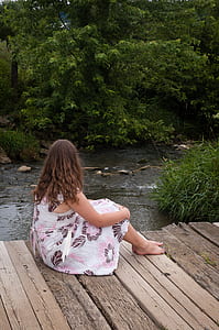 woman sitting while looking at river thumbnail