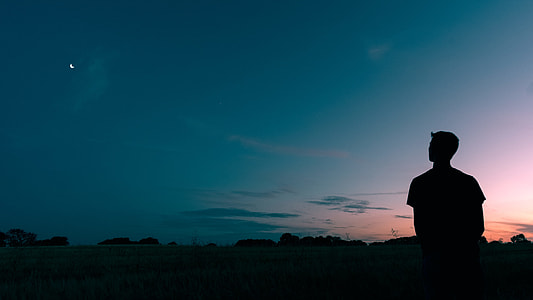 silhouette photography of man standing and starring moon thumbnail